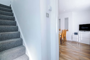 A modern interior with a staircase, a dining area, and a flat-screen TV. - Nottingham | Modern Home | Free Parking | Sleeps 5 (Beeston)