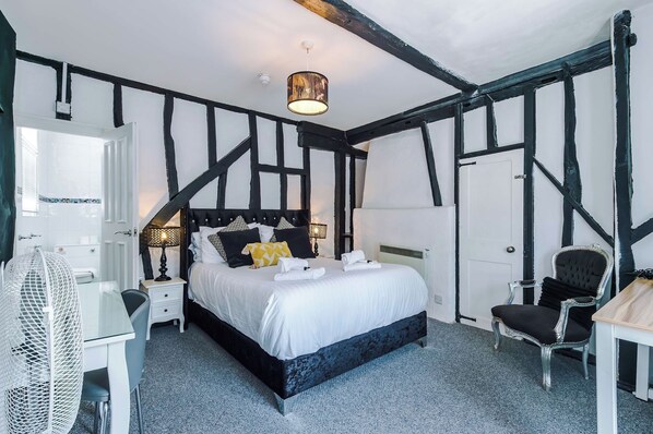 Une chambre à coucher avec un grand lit, une table de chevet, une chaise et une petite table avec une lampe.