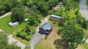 Vue aérienne d’une propriété rurale comprenant une grande grange, une maison plus petite et une allée.
