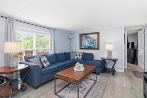A living room with a sectional sofa, a wooden coffee table, a painting on the wall, and a view through the window. - White River Retreat Escape - Hot Tub, 5 BRs, 2 Homes (West Fork)