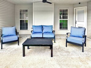 A covered patio with a sofa and two chairs, a table, and a ceiling fan. - The Ultimate Fayetteville Retreat - Two Homes, 8 BRs, 5 Mi to U of A (Fayetteville)