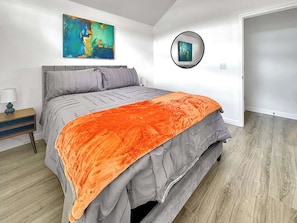 A bedroom with a bed, a nightstand, a painting, and a mirror. - The Ultimate Fayetteville Retreat - Two Homes, 8 BRs, 5 Mi to U of A (Fayetteville)