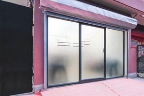 A storefront with a sliding glass door, a metal awning, and a red and black fence. - Hotel O Shalimar Railway Junction Howrah (Howrah)