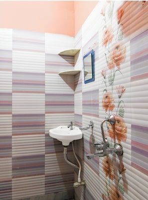 Un bany amb parets de rajola rayada, un lavabo i un mirall.