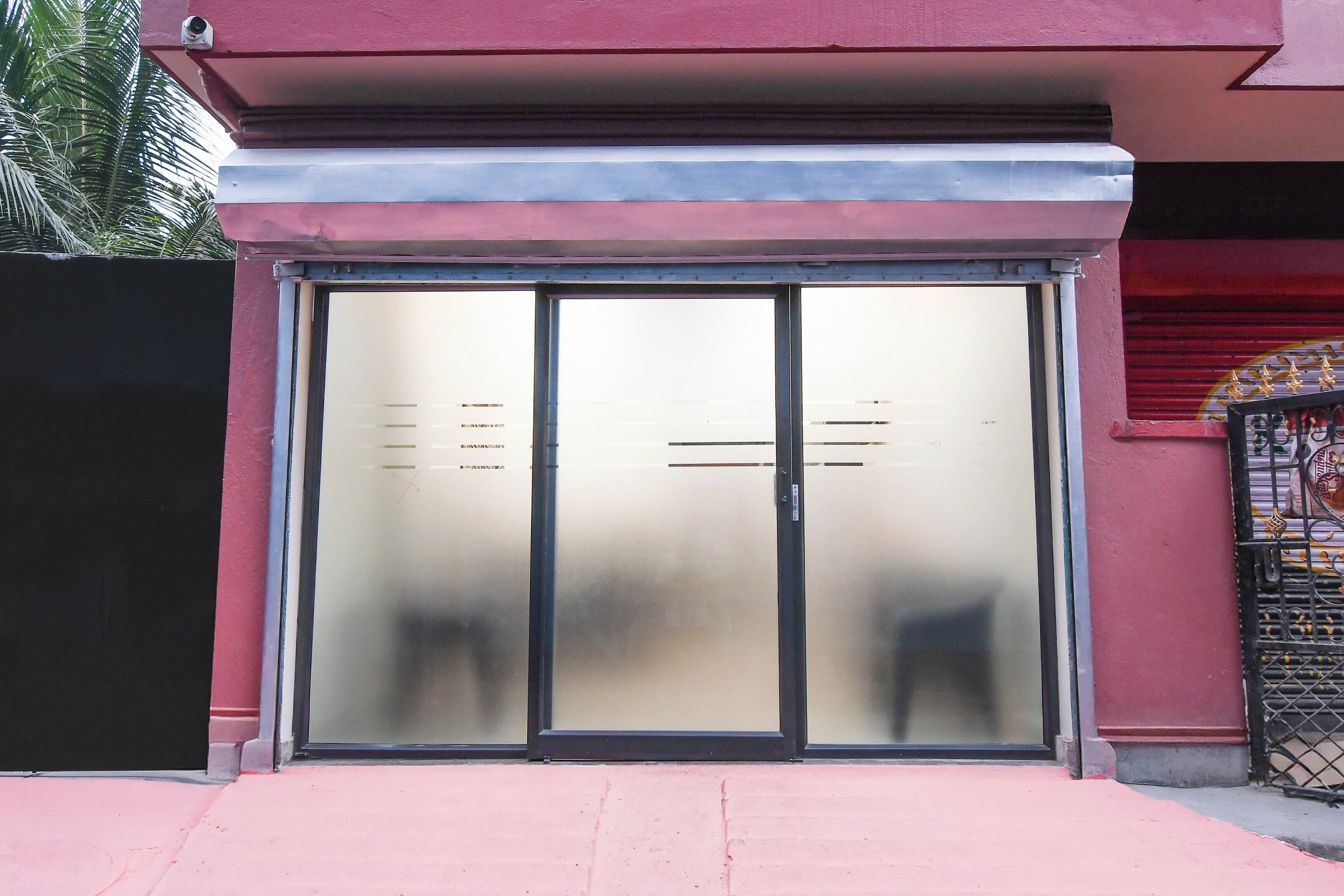 Una entrada de edificio con puerta de cristal y reja de metal.