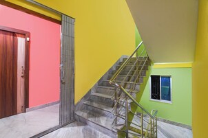 A staircase with metal railings leading to a landing, adjacent to a door with a metal gate.