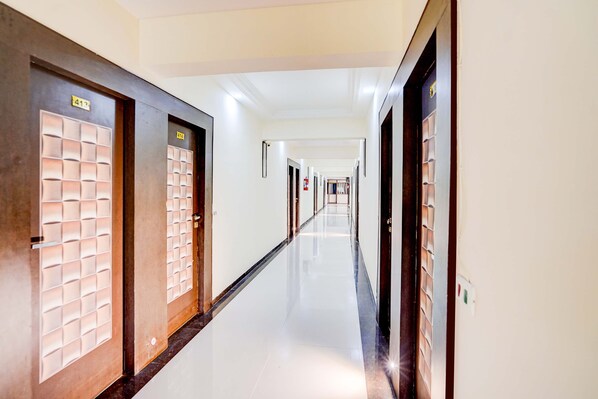 A long, narrow hallway with doors on both sides, leading to individual rooms. - Collection O Infocity Metro Station (Gandhinagar)