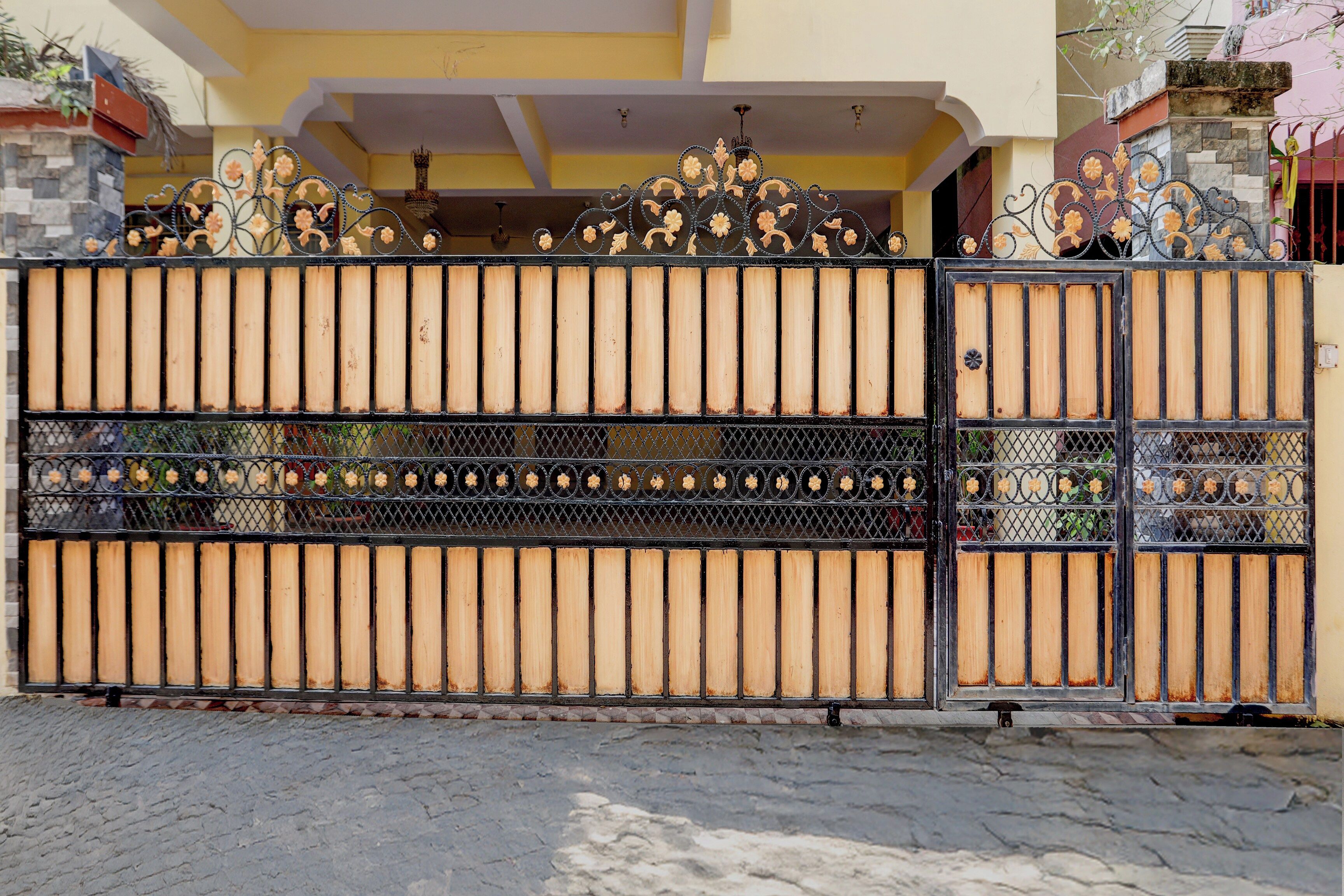 Una entrada con puerta y un diseño de metal decorativo, junto a un pilar de piedra.