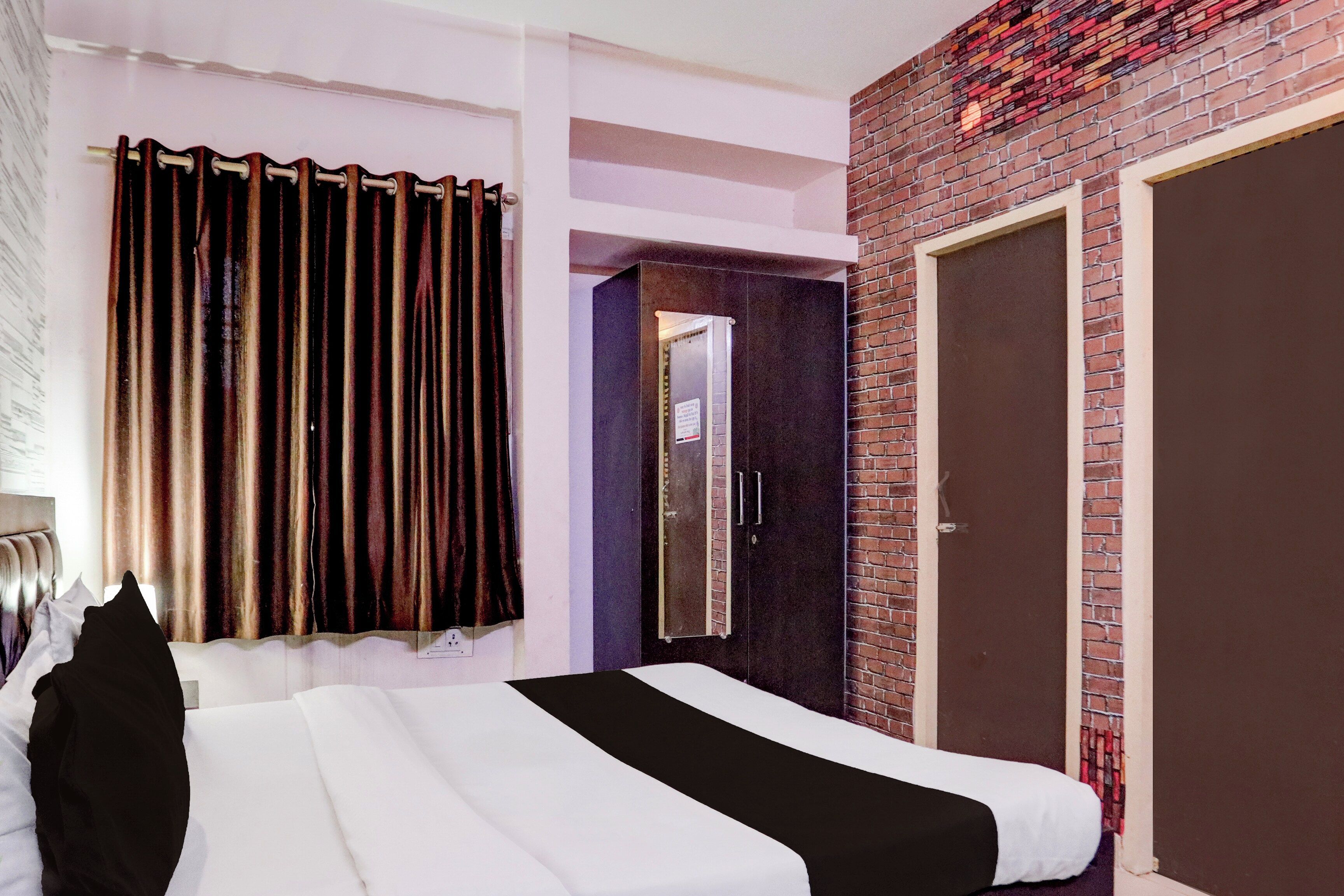 A hotel room with a bed, a wardrobe, a mirror, and a door.