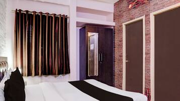 A hotel room with a bed, a wardrobe, a mirror, and a door.