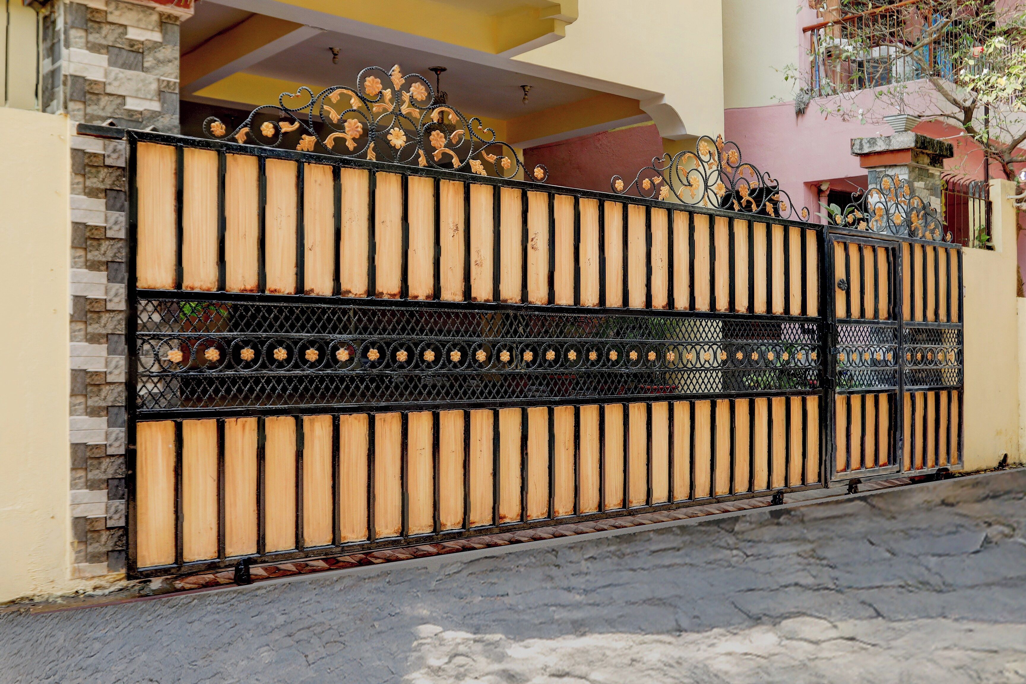 A gated entrance with a decorative metal gate and a brick wall.