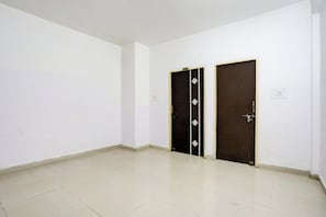 A room with two dark-colored doors, white walls, and a tiled floor. - Super Hotel O A.N College Patna (Patna)