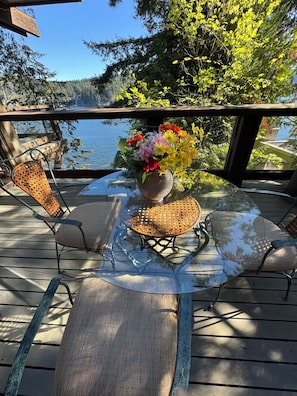 A deck with a glass table and wicker chairs, overlooking a body of water. - Luxury Waterfront Villa Ocean Views and Private Dock North Vancouver (North Vancouver)