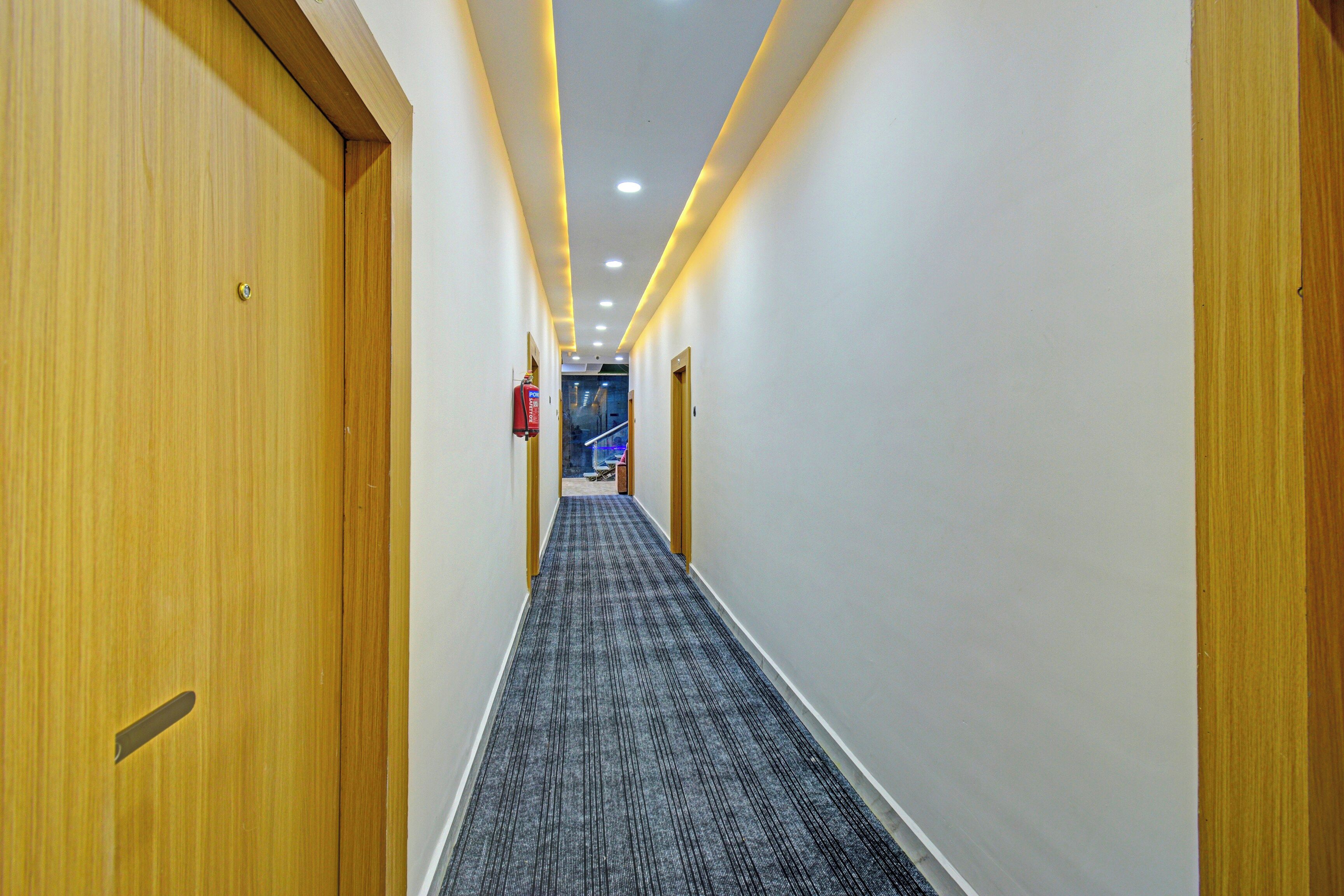 Un pasillo de hotel con puertas de madera, piso alfombrado e iluminación empotrada.
