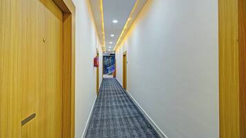 Un pasillo de hotel con puertas de madera, piso alfombrado e iluminación empotrada.