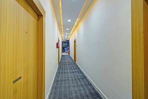 A hotel hallway with wooden doors, a carpeted floor, and recessed lighting.