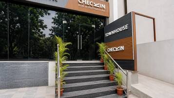 Entrada de un hotel con una escalera que conduce a la recepción, flanqueada por macetas con plantas.