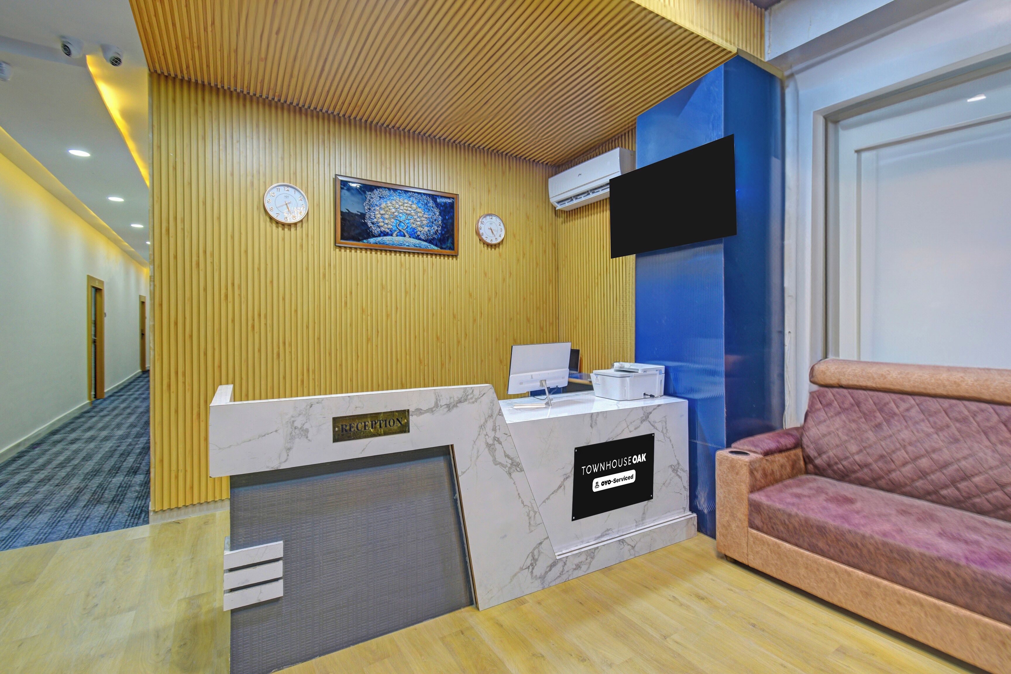 A reception area with a marble counter, a reception sign, a clock, and a mounted painting.