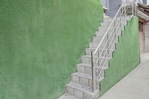 Escadaria com corrimãos de metal que leva à entrada de um edifício.