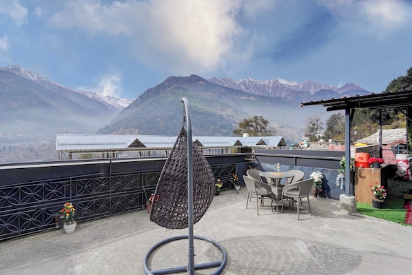 A terrace with a wicker chair, a table, and potted plants. - Hotel O Vashisht Temple (Manali)