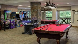 A pool table with a red felt surface, arcade games, and a billiards table in a room with carpet flooring and a stone pillar. - Sheraton Mountain Vista - 1 Bedroom (Avon)