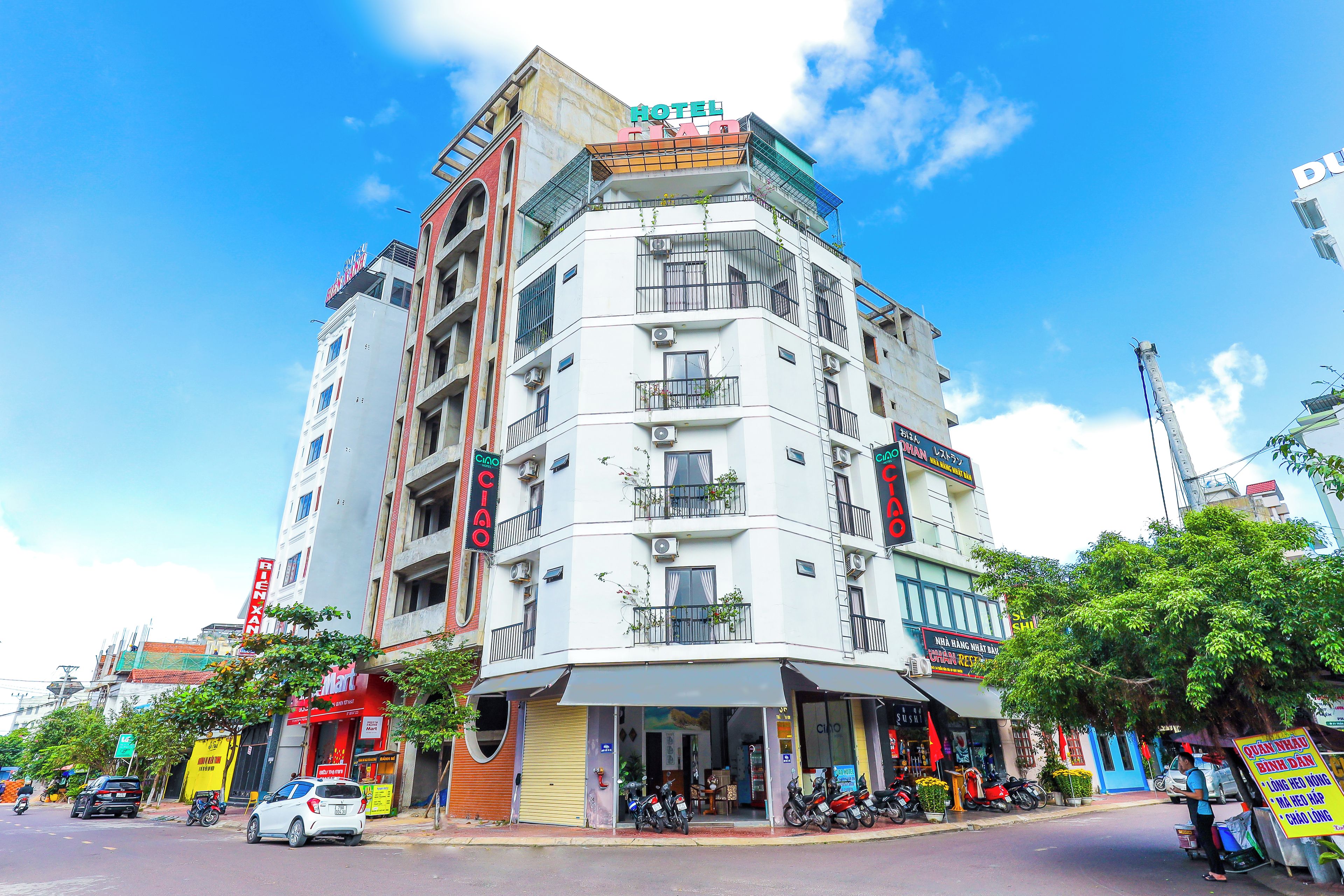A multi-story hotel with balconies, a ground-level restaurant, and various signage indicating amenities and services.