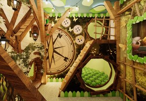 A whimsical indoor setting with a large wooden clock, a green circular window, and a wooden fence. - 10bd house with private pool and game room (Clermont)