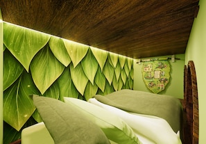 Una habitación con un papel tapiz estampado con hojas, techo de madera y una cama con almohadas.