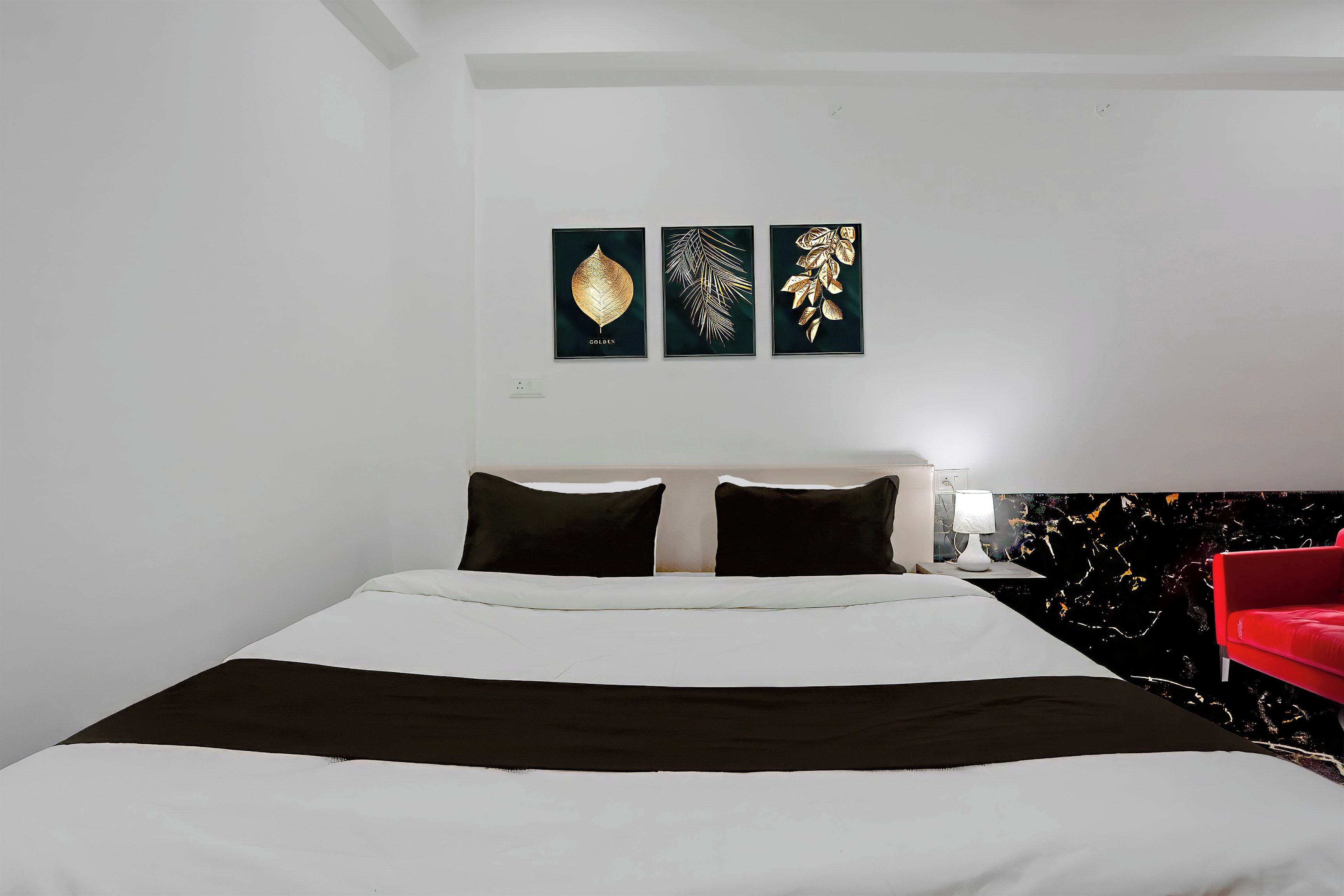 Habitació d'hotel amb un llit, una cadira vermella i obra d'art a la paret.