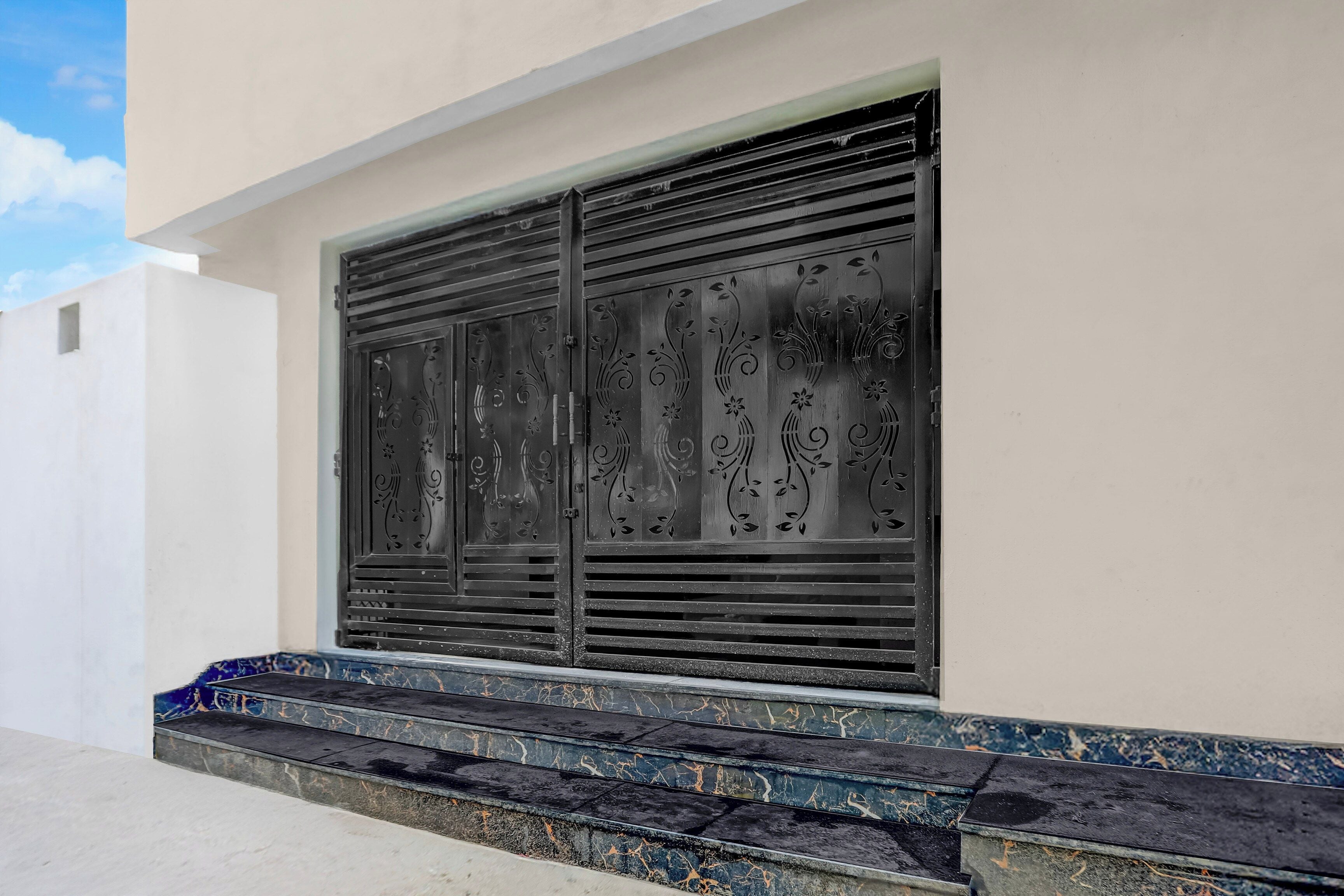 Edifici amb una gran porta metàl·lica ornamentada i un conjunt d'escales de marbre que condueixen a l'entrada.