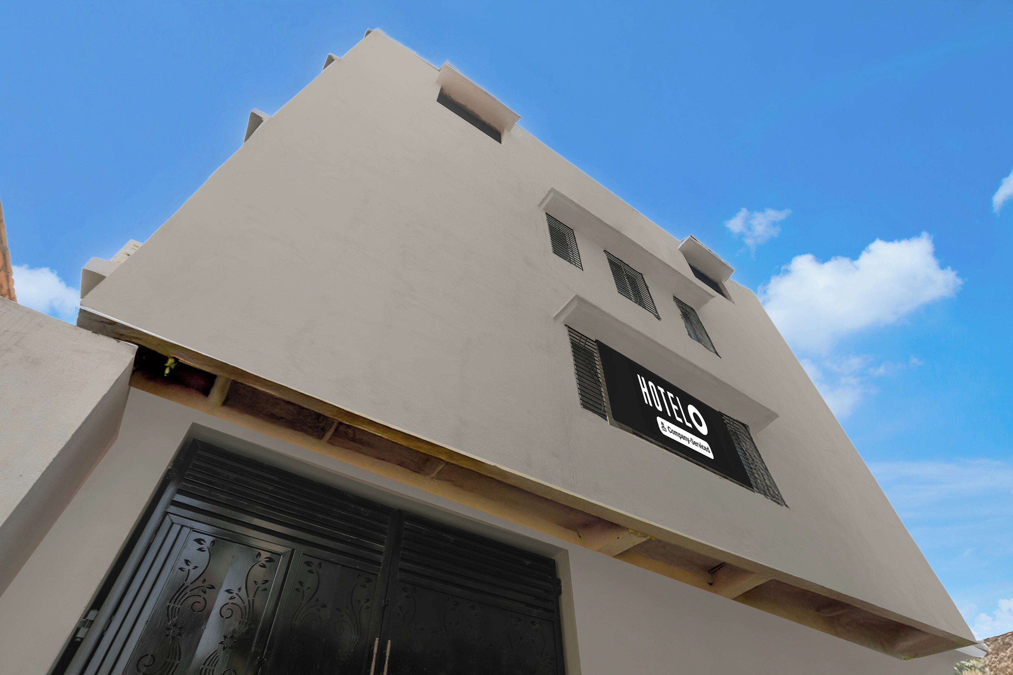 Ein Hotelgebäude mit einer flachen Fassade, einem großen Eingang mit einem Metallgitter und einem Schild, das es als betriebliches Hotel kennzeichnet.