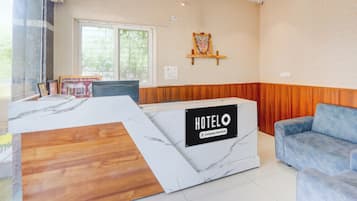 Een hotel receptiebalie met een marmeren blad, een blauwe bank en een religieus kunstwerk aan de muur.