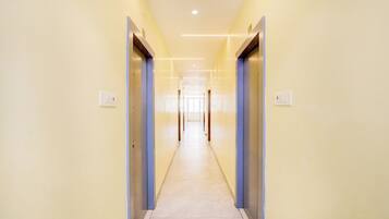 Un pasillo largo y estrecho con puertas a ambos lados, que conduce a una habitación luminosa al final.