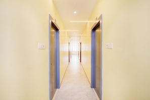 A long, narrow hallway with doors on both sides, leading to a bright room at the end.
