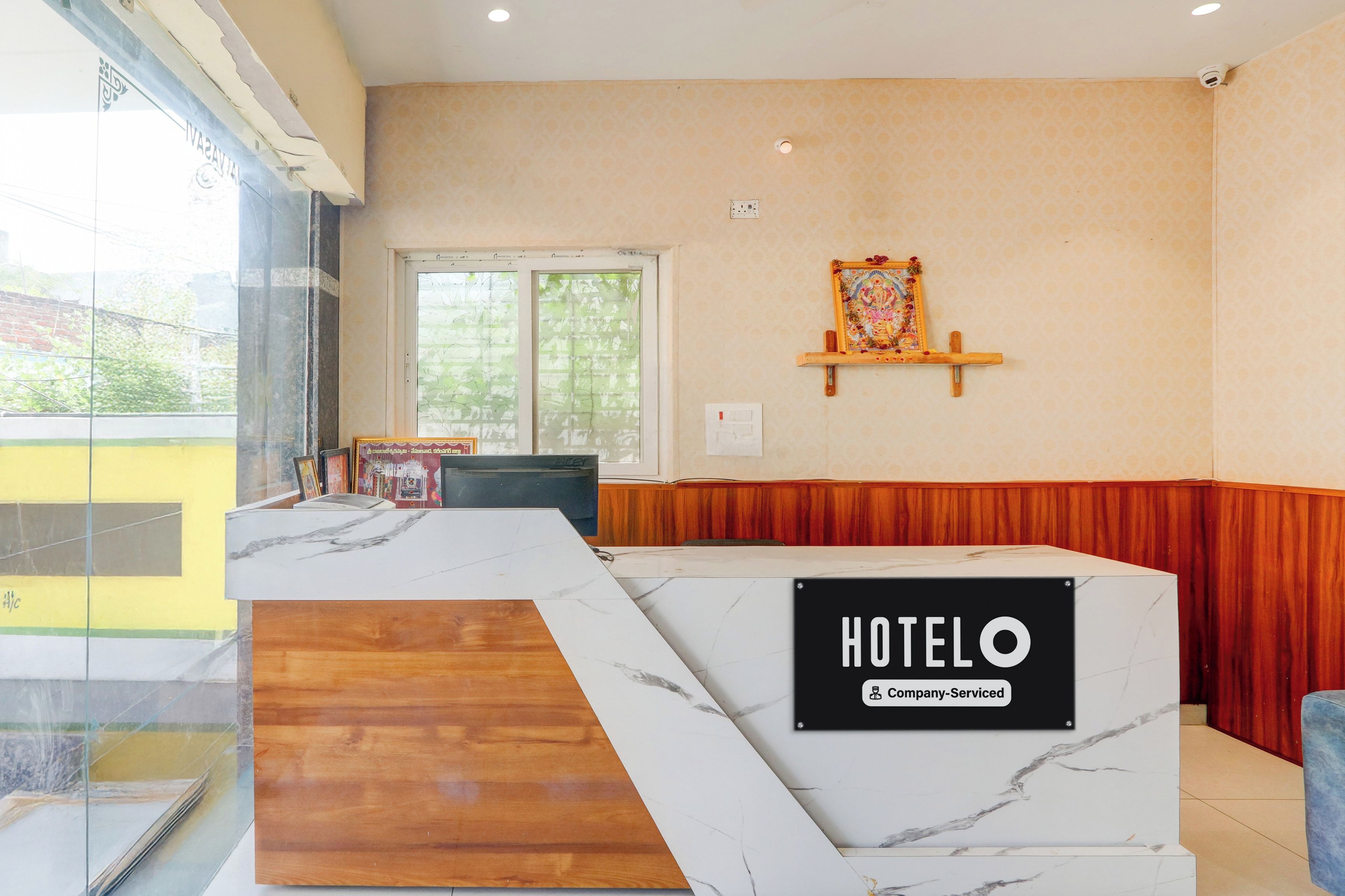 Zona de recepción de un hotel con mostrador de mármol, sección de madera y un cartel en la pared que indica 'HOTEL'.
