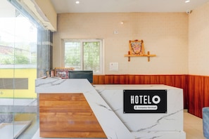 A hotel reception area with a marble counter, a wooden section, and a wall-mounted sign indicating 'HOTEL'.