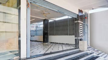 Una entrada de hotel con suelo de baldosas, ventilador de techo y portón metálico.