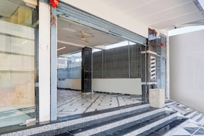 A hotel entrance with a tiled floor, a ceiling fan, and a metal gate.