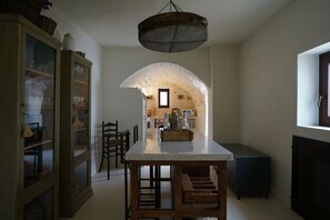 Eine Küche mit einer zentralen Kochinsel, Holzkästen, einer Hängeleuchte und einem Einbauschrank mit Glastüren.