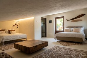 Ein Schlafzimmer mit zwei Betten, einem Holztisch, Teppichen mit Muster und Blick durch eine Tür.