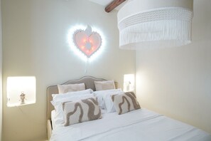 A bedroom with a bed, a heart-shaped light fixture, and a hanging light fixture. - Trulli San Domenico by Perle di Puglia (Martina Franca)