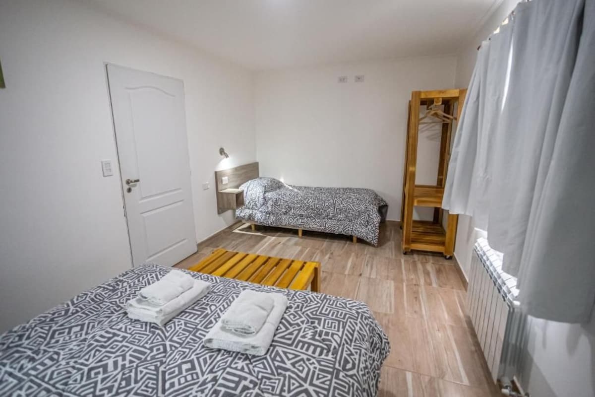 Una sistemazione semplice, con una singola stanza arredata con un letto, una panca, un comodino, un armadio e un termosifone.