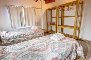 Une chambre avec deux lits, une armoire en bois et une fenêtre avec des rideaux.
