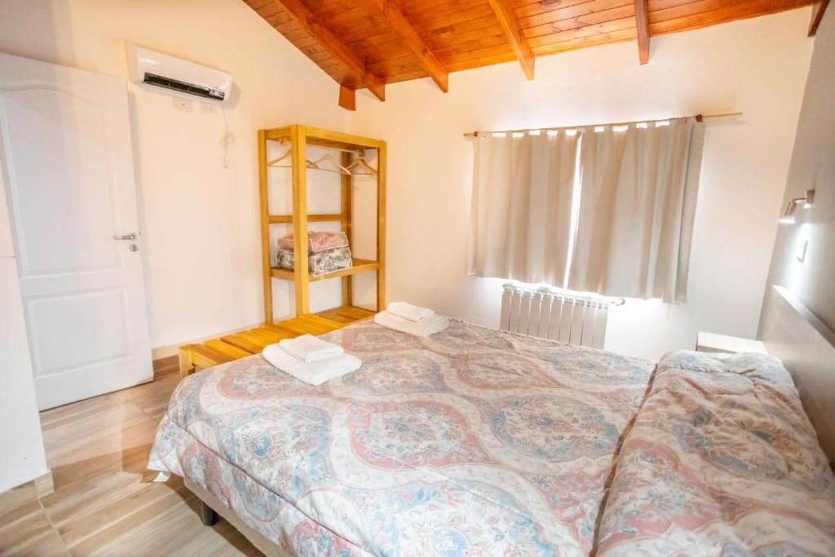 Una camera da letto con un letto, un armadio in legno, un termosifone e una finestra con tende.