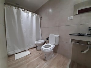 Un bagno con due servizi igienici, una tenda da doccia, un lavandino e uno specchio.