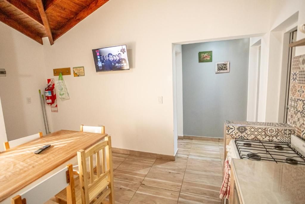 Una cocina con una mesa y sillas de madera, un televisor montado en la pared y una estufa con diseños.