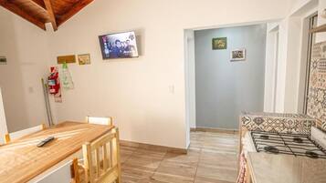 Una cocina con una mesa y sillas de madera, un televisor montado en la pared y una estufa con diseños.