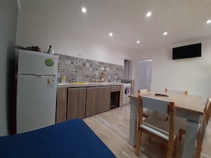 Una cucina funzionale con frigorifero, mobili in legno, paraschizzi decorato e zona pranzo con tavolo e sedie.