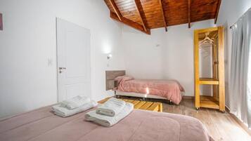 Un dormitorio con cama, mesita de noche, armario y puerta.