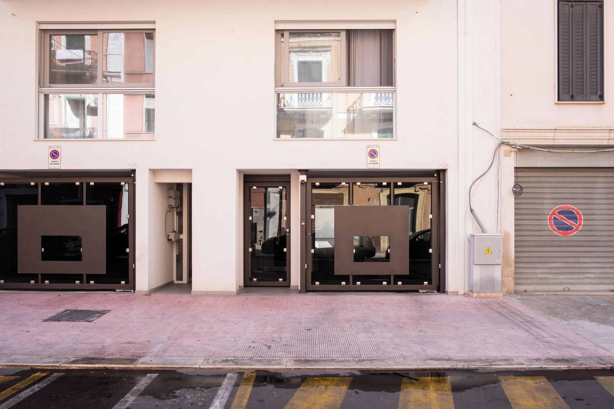 Ein Gebäude mit drei Portalen, jedes mit einer großen Glasscheibe. Keine Fenster oder Schilder sind sichtbar, die den Verwendungszweck des Gebäudes angeben.